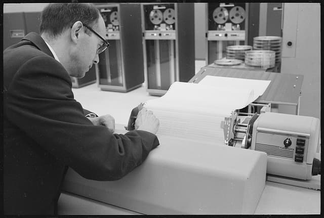 Technician reading IBM computer printout tracking Vanguard 1 in 1958.
